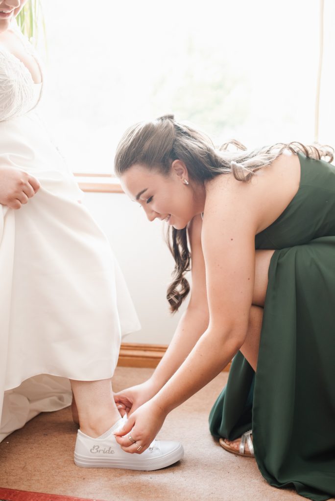 Bridesmaids helping bride into her wedding dress before ceremony
