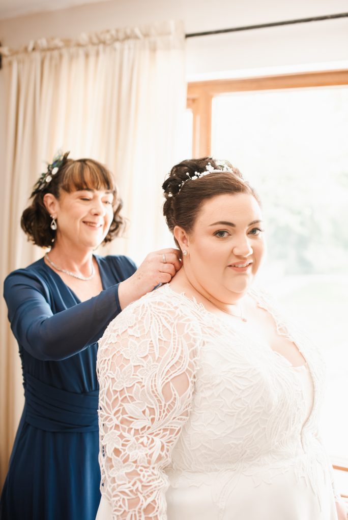 Bride's mother helping bride into her wedding dress before ceremony