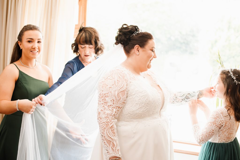 Bridesmaids helping bride into her wedding dress before ceremony