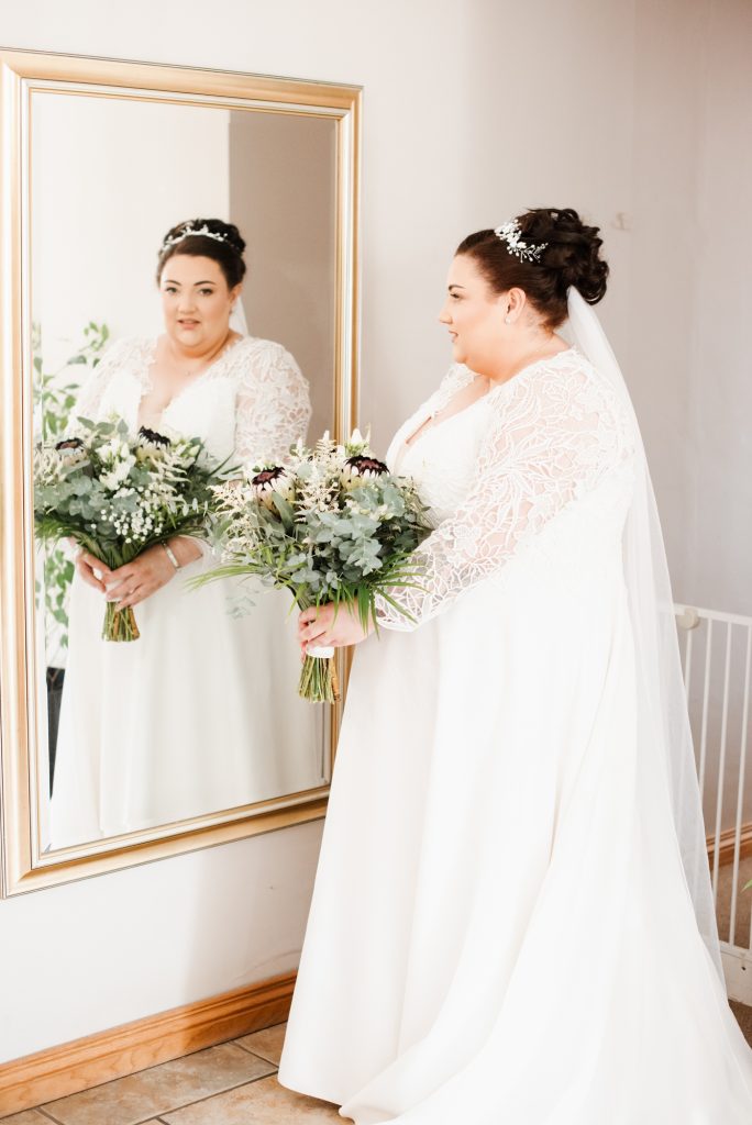 Candid moment of bride looking to the mirror while preparing for wedding day