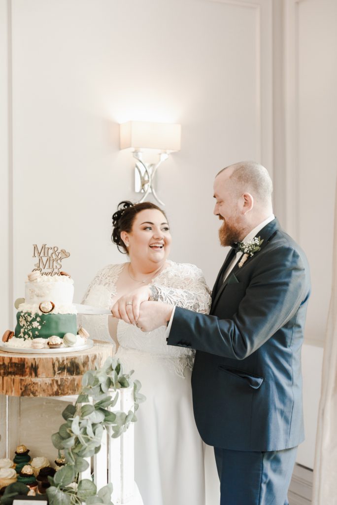 Happy couple sharing a moment of cutting a wedding cake at Millbrook Lodge