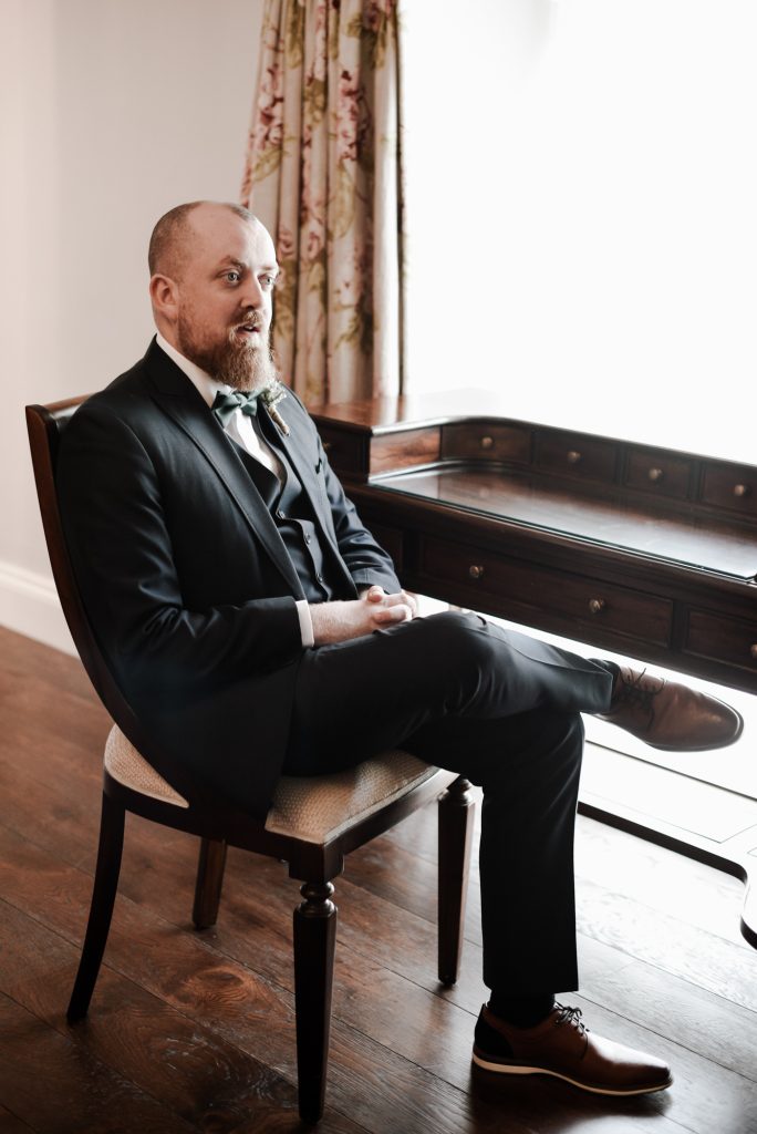 Groom sitting in wedding suite at the window at Millbrook lodge